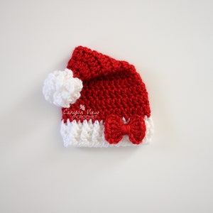 May include: A red and white crocheted Santa hat with a white pom-pom and a red bow. Canyon View Crochet.
