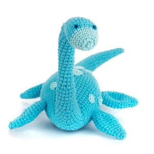 May include: A crocheted blue and white plush toy shaped like a dinosaur. The toy has a long neck and a small head with two black eyes.