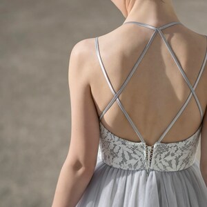 May include: A gray tulle dress with a white lace bodice and a criss-cross strap back.