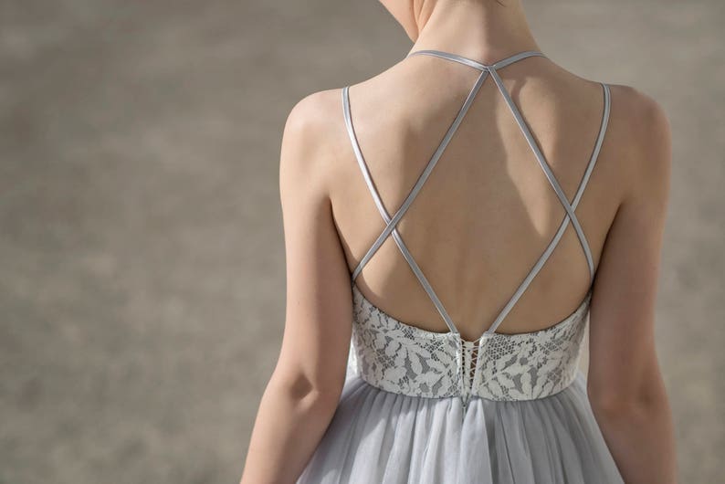 May include: A gray tulle dress with a white lace bodice and a criss-cross strap back.