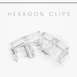 May include: Clear plastic hexagon clips for hanging curtains or other items. The clips are designed to fit over a curtain rod or other similar object.