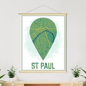 Puede incluir: Un mapa verde y amarillo de St. Paul, Minnesota, en forma de pin, sobre un fondo blanco con un efecto acuarela azul claro. El texto "ST PAUL" está debajo del mapa en una fuente amarilla.