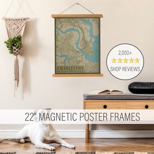 May include: A 22-inch magnetic poster frame with a map of Charleston, South Carolina. The map is printed on a beige background with green and blue accents. The frame is made of wood and has a simple, modern design. The text "CHARLESTON" and the coordinates "32-5351.8"N 80°01′27.8"W" are printed on the map.