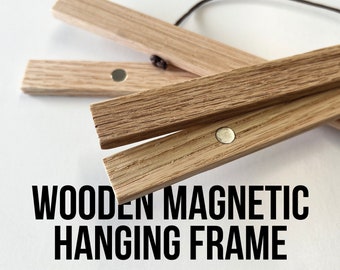 May include: A wooden magnetic hanging frame with two magnets visible. The frame is made of natural wood and has a simple design.