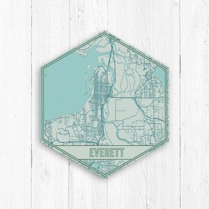 May include: A hexagonal map of Everett, Washington, with a blue and green colour scheme. The map is on a white wood background. The city name, "EVERETT", is printed in a green rectangle at the bottom of the map.
