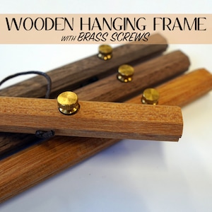May include: Wooden hanging frame with brass screws. The image shows several wooden bars in varying shades of brown, each with a brass screw. The text "WOODEN HANGING FRAME WITH BRASS SCREWS" is at the top of the image.