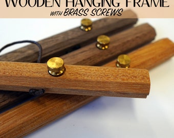 May include: Wooden hanging frame with brass screws. The image shows several wooden bars in varying shades of brown, each with a brass screw. The text "WOODEN HANGING FRAME WITH BRASS SCREWS" is at the top of the image.