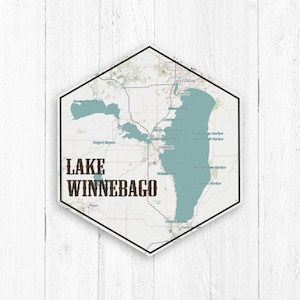 May include: A map of Lake Winnebago in Wisconsin, showing the lake's outline and surrounding towns. The map is in a hexagonal frame with the words "Lake Winnebago" in brown text.