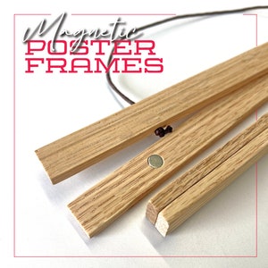 Puede incluir: Primer plano de un conjunto de tres marcos de póster magnéticos de madera. Los marcos están hechos de madera natural y tienen un diseño simple y minimalista. Los marcos se mantienen unidos por imanes, que son visibles en la imagen.