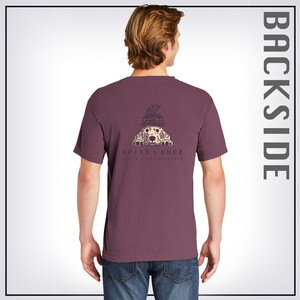 May include: A maroon t-shirt with a graphic of a dog peeking out from behind a stack of books. The text "SPIKE & ENDE DOG-FRIENDLY BOOKSHOP" is printed below the graphic.