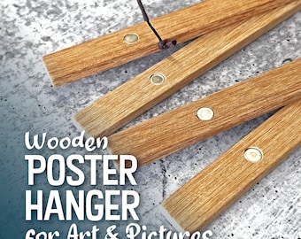 Puede incluir: Un colgador de póster de madera con cuatro barras de madera marrón y clips metálicos. El colgador está plegado y el texto "Wooden POSTER HANGER for Art & Pictures" es visible en primer plano.