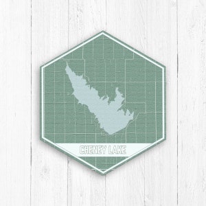 Pode incluir: Um sinal hexagonal verde com borda branca e o texto "CHENEY LAKE" em branco. O sinal tem um mapa de um lago dentro.