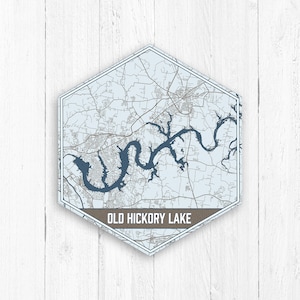 May include: A hexagonal map print of Old Hickory Lake, North Carolina. The map is in shades of blue and white, with a brown border and text. The map is on a white wood background.