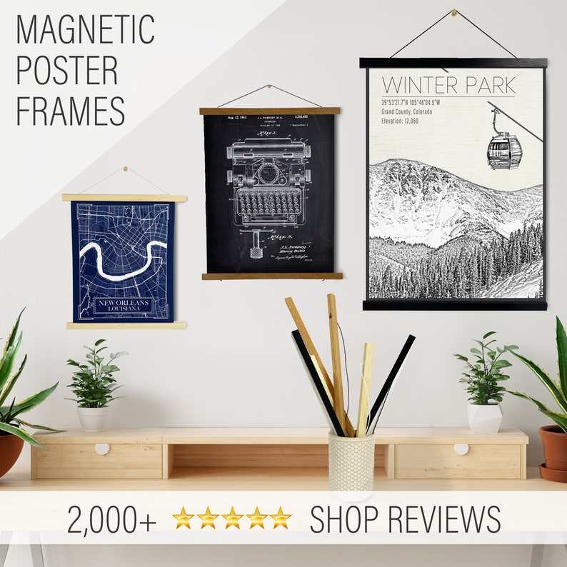 May include: Three black framed posters with wooden dowels hanging on a white wall. The posters feature a vintage typewriter patent drawing, a map of New Orleans, and a black and white illustration of a mountain scene with a gondola.