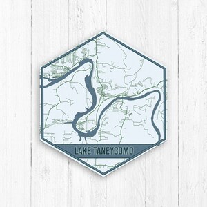 May include: A hexagonal map print of Lake Taneycomo, Missouri, with a blue and green color scheme. The map shows the winding river and surrounding roads. The text "LAKE TANEYCOMO" is printed in blue at the bottom of the map.