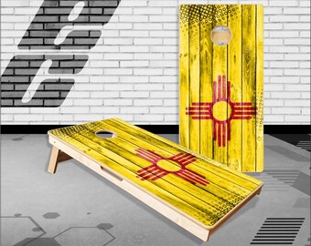 May include: A wooden cornhole board with a yellow and red design featuring the state flag of New Mexico. The flag has a red symbol of the sun with a circle in the center and four red rays extending from the circle.