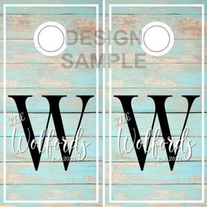 May include: Two blue wooden cornhole boards with white frames. Each board has a black letter W with the text "The Wolffords Est. 2021" in white. There is a white circle in the upper right corner of each board.
