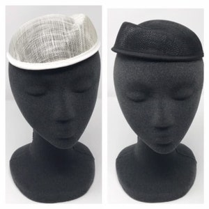 May include: Two hats on mannequin heads. The hat on the left is white and the hat on the right is black.