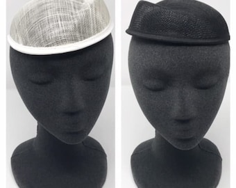 May include: Two hats on mannequin heads. The hat on the left is white and the hat on the right is black.