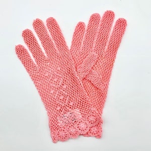 Könnte beinhalten: Ein Paar rosa Häkelhandschuhe mit zarter Spitzenborte.