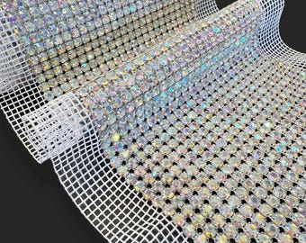 May include: A roll of iridescent clear rhinestone mesh fabric. The mesh is white and the rhinestones are clear with a rainbow effect.