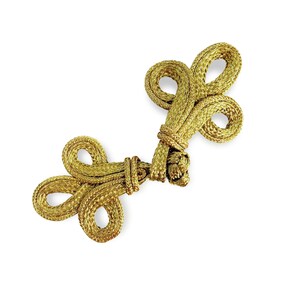 Könnte beinhalten: Goldfarbener geflochtener Knebelverschluss. Der Verschluss weist eine Reihe von Schlaufenknoten auf, die ein elegantes und dekoratives Element bilden. Das aufwendige Design und der metallische Glanz deuten auf eine hochwertige Verarbeitung hin, die sich zum Verzieren von Kleidungsstücken oder Accessoires eignet.