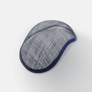 K&ouml;nnte beinhalten: Eine marineblaue Sinamay-Hutbasis, eine Art Stroh, das f&uuml;r die Hutmacherei verwendet wird, mit einer gewebten Textur. Die Basis ist oval geformt und hat einen leicht gekr&uuml;mmten Rand.