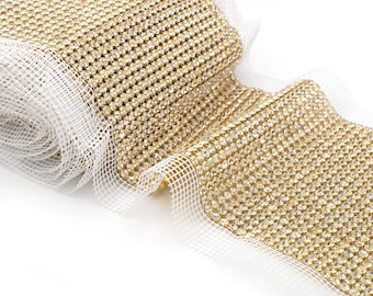 May include: A roll of gold rhinestone trim with a white mesh backing. The trim is made of small, round rhinestones that are closely spaced together.