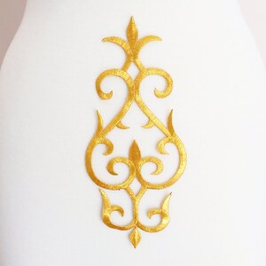 Puede incluir: Aplique bordado en oro con un diseño floral decorativo. El aplique es perfecto para añadir un toque de elegancia a la ropa, las manualidades o la decoración del hogar.