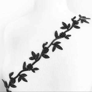 Pode incluir: Trimming floral preto com contas com um design de videira. O trimming é feito de pequenas contas pretas e tem um visual delicado e feminino.