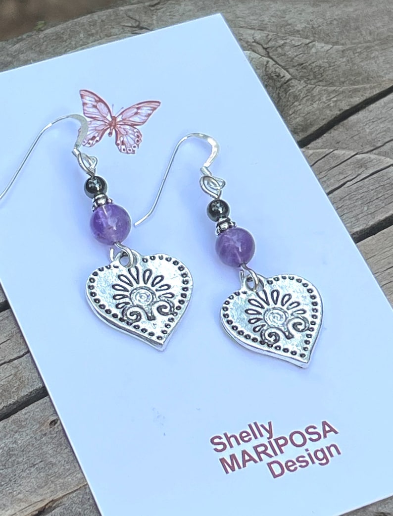 Pode incluir: Brincos de cora&ccedil;&atilde;o de prata com contas de ametista e hematita. Os brincos t&ecirc;m um design detalhado e s&atilde;o etiquetados como "Shelly MARIPOSA Design".
