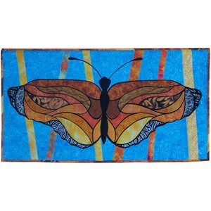 May include: A colorful butterfly quilt with a stained glass design. The butterfly is brown, orange, and yellow with black accents. The background is a bright blue with yellow and orange stripes.