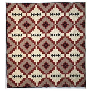 May include: A quilt with a geometric pattern in shades of red, white, black, and gray. The pattern is made up of squares and diamonds.
