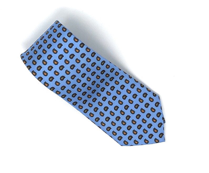 May include: A light blue tie with a paisley pattern in shades of brown and orange.