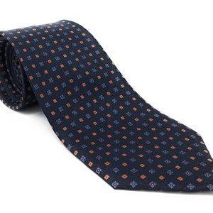 May include: A dark blue necktie with a repeating pattern of small orange and blue squares.