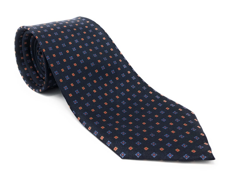 May include: A dark blue necktie with a repeating pattern of small orange and blue squares.