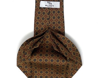 May include: A brown and gold patterned silk tie with a black label that reads "WILMOK ROME".