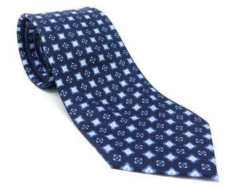 May include: A blue patterned silk tie with a white background. The pattern is a repeating geometric design.