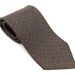 May include: A patterned tie with a repeating floral design. The tie features a dark green background with a pattern of red, blue, and tan circular motifs. The tie is made of a smooth fabric and is displayed on a white background.