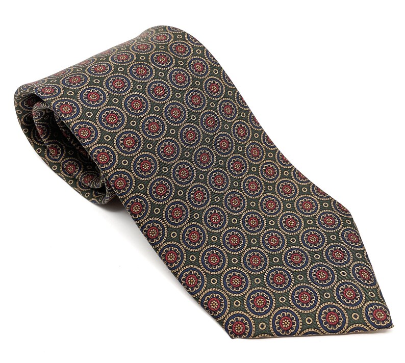 May include: A patterned tie with a repeating floral design. The tie features a dark green background with a pattern of red, blue, and tan circular motifs. The tie is made of a smooth fabric and is displayed on a white background.