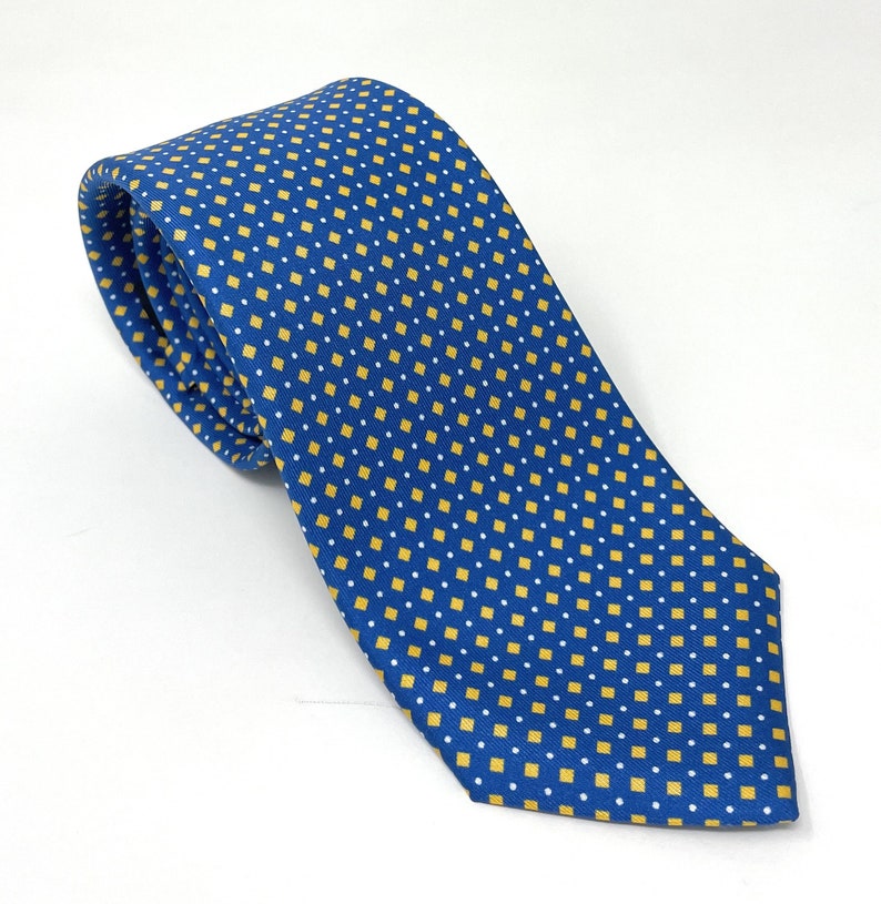 May include: A blue silk tie with a yellow and white geometric pattern.
