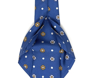 May include: A blue silk tie with a white polka dot and floral pattern. The tie has a label that reads "WILMOK  ROME".