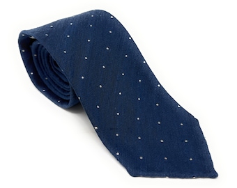 Puede incluir: Una corbata azul marino con un estampado de lunares blancos. La corbata está hecha de una tela texturizada y se muestra sobre un fondo blanco. La corbata está anudada en la parte superior.