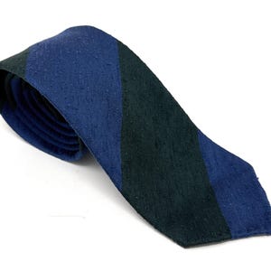 May include: A dark blue and green striped tie made of a textured fabric.
