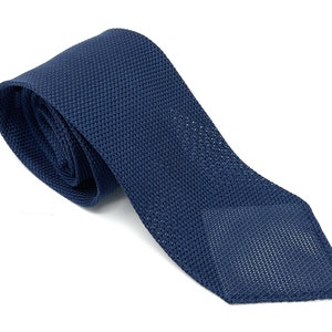 May include: A dark blue knitted tie with a textured pattern.