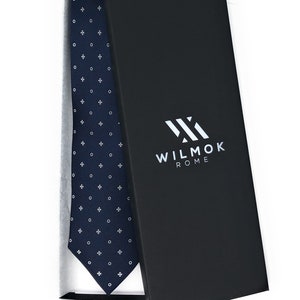 May include: A navy blue tie with a white pattern of circles and crosses in a box with the text "WILMOK ROME" on the box.