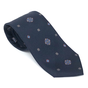 May include: A dark blue patterned tie with a repeating geometric design in shades of blue, red, and brown.