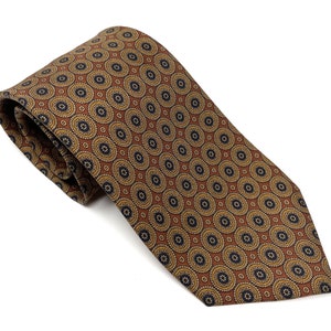 May include: A brown tie with a repeating circular pattern in gold and navy blue. The tie is made of a smooth fabric and is neatly folded, showcasing the intricate design. The tie is a classic accessory.