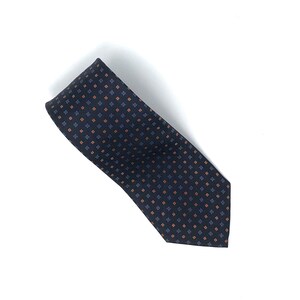 May include: A dark blue necktie with a repeating pattern of small orange and blue squares.