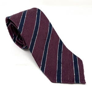 May include: A burgundy and navy blue striped tie with a textured surface.